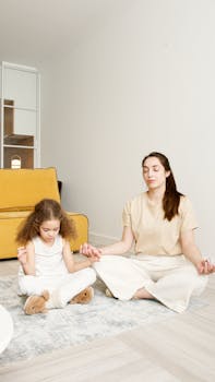Caucasian mother and daughter meditating peacefully indoors on a calm day.