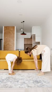 Mother and daughter bonding through stretching exercises in a cozy living room setting.