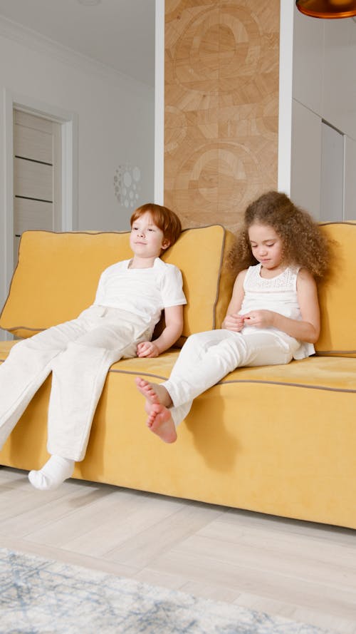 Two Children Sitting on the Yellow Couch