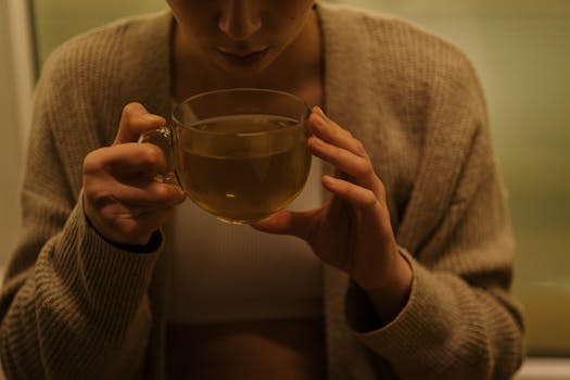 A woman enjoys a relaxing cup of tea, creating a cozy and tranquil atmosphere.