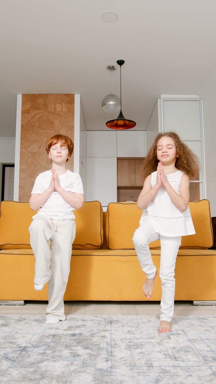 Two Children Practising Yoga At Home 