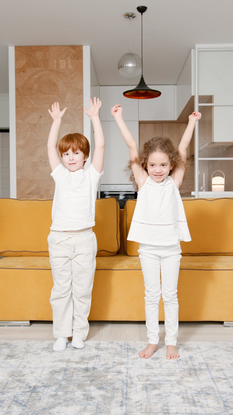 Two Children Standing With Their Arms Raised Up In The Air