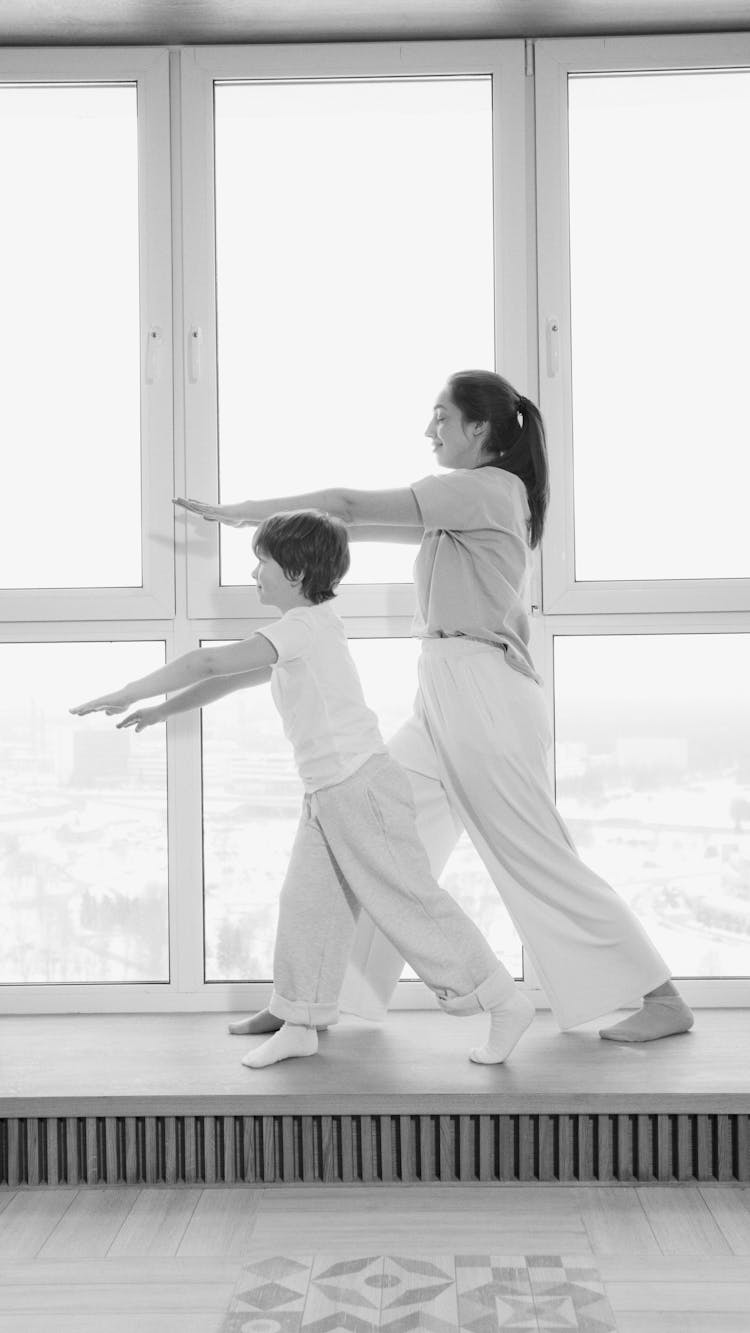 Mother And Son Exercising Beside The Glass Window