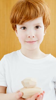Charming portrait of a young boy with red hair holding wooden blocks, showcasing innocence.