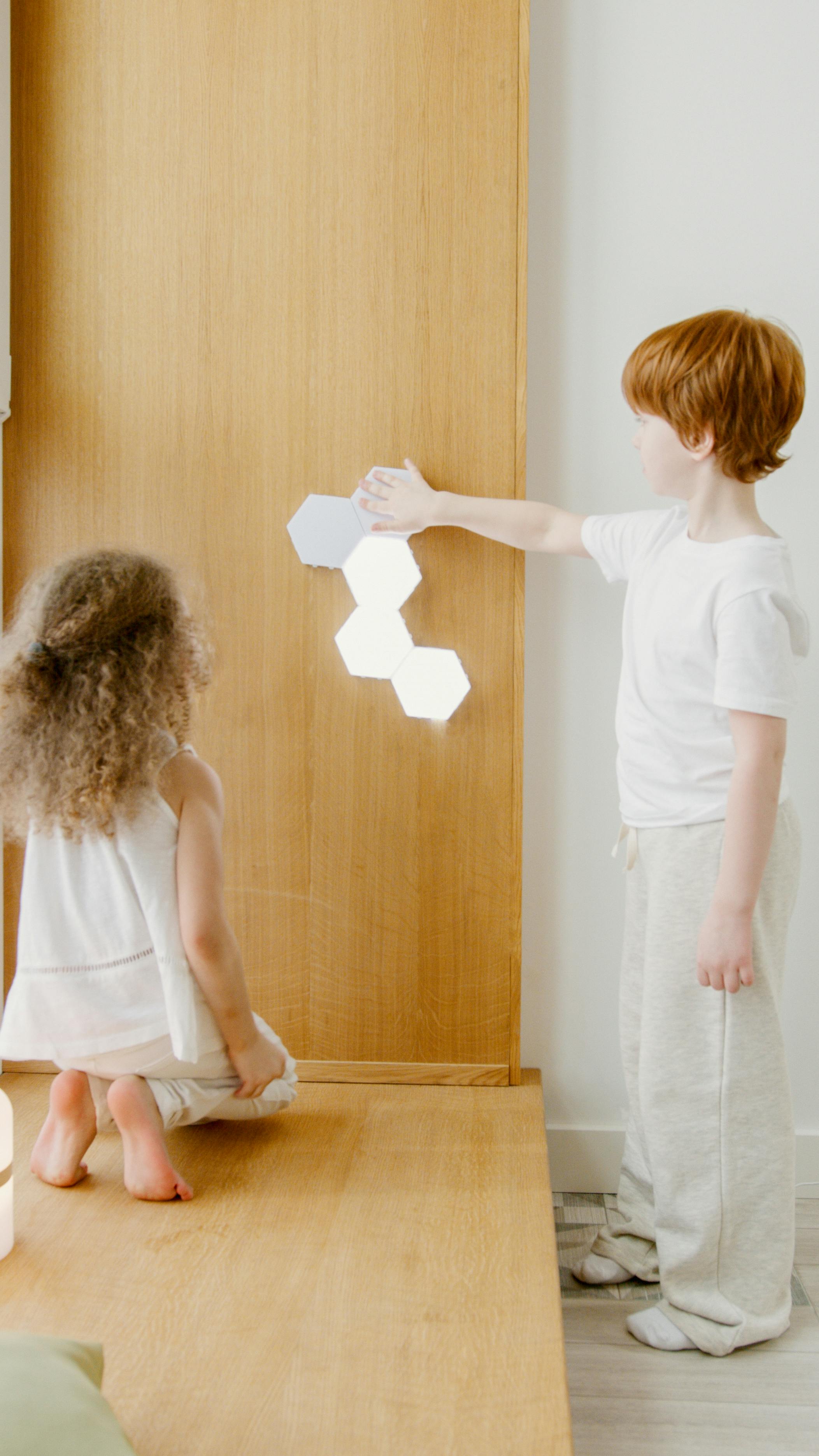 Two children explore interactive wall art in a modern indoor setting, showcasing creativity and technology.