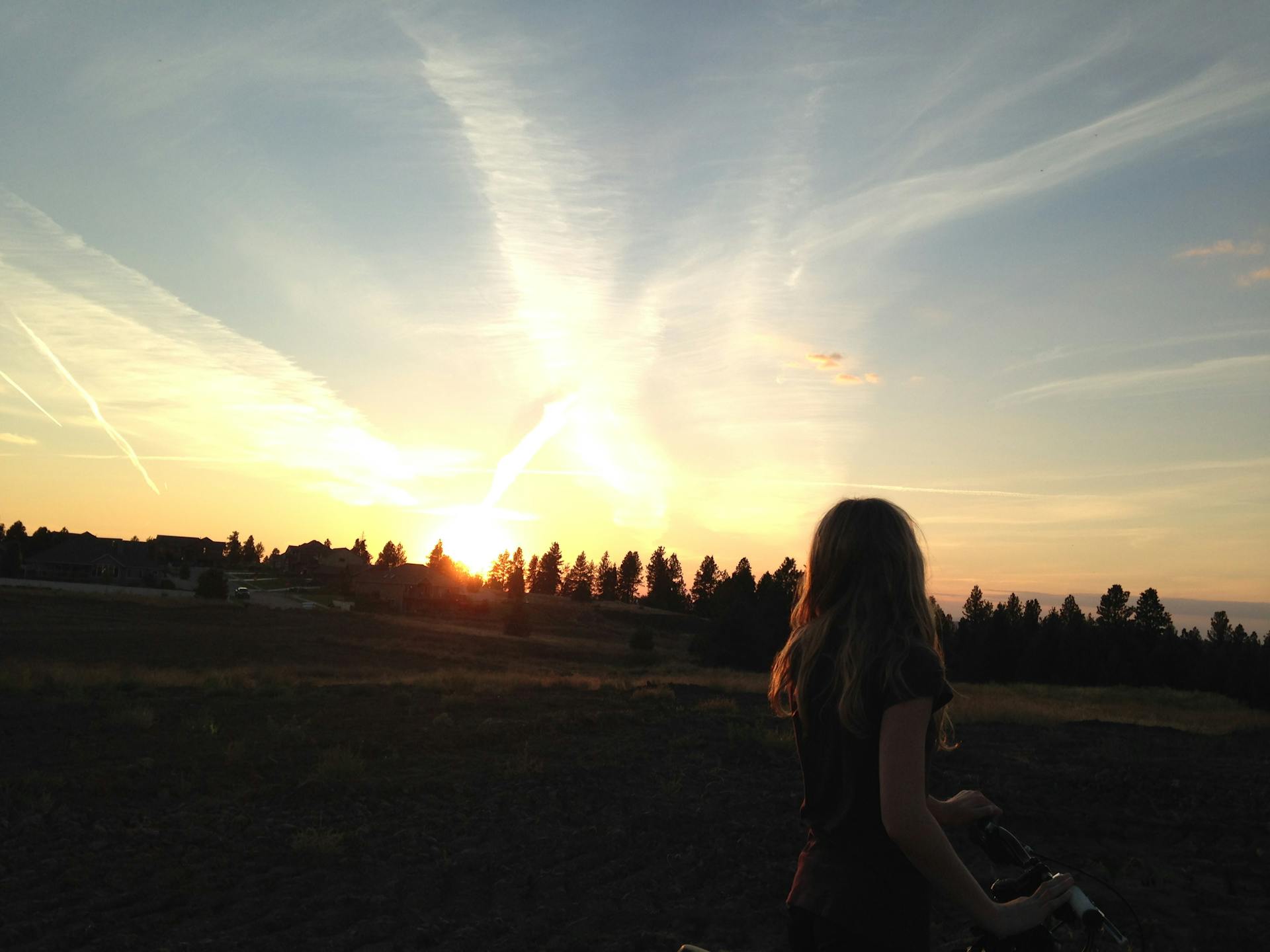 A woman silhouetted against a picturesque Spokane sunset. Perfect blend of nature and serenity.