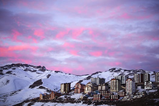 在充满活力的粉红色日落天空下，白雪覆盖的山城令人惊叹