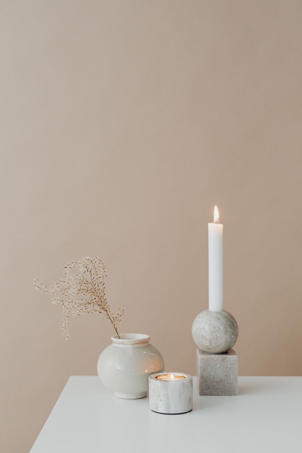 Ceramic vase and candle arranged as a quiet still life on a neutral backdrop