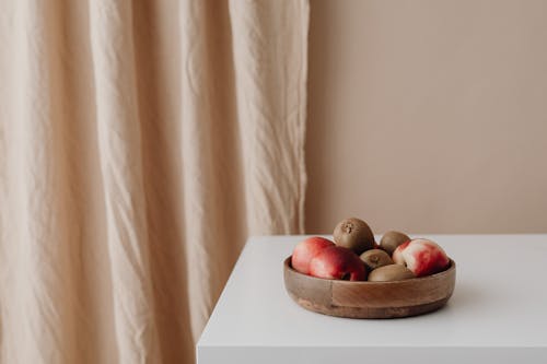 Photograph of Kiwis and Apples in a Wooden Bowl