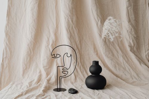 Free A minimalist still life features a sculpture, black vase, dry grass, and artistic decor. Stock Photo