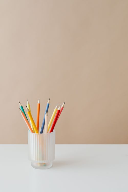 Free Vibrant colored pencils neatly arranged in a glass holder on a white desk, ideal for creative themes. Stock Photo