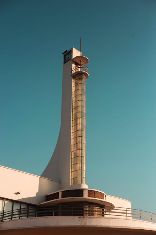 Low angle of modern tower located on terrace of contemporary building with glass structure in front and viewing platform at top on sunny day