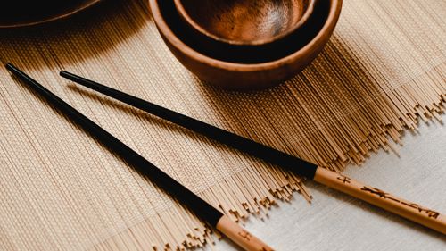 Free Close-up of wooden bowls and chopsticks on a bamboo mat, showcasing minimalist Asian dining ware. Stock Photo