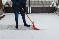 Photo of a Person in a Blue Jacket Shoveling White Snow