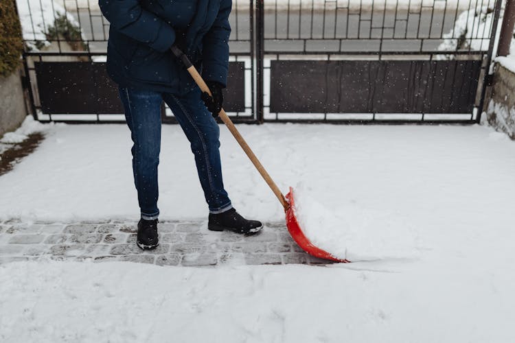 Photo Of A Person In A Blue Jacket Shoveling White Snow