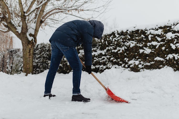 Man Clearing Snow In Winter Outdoors