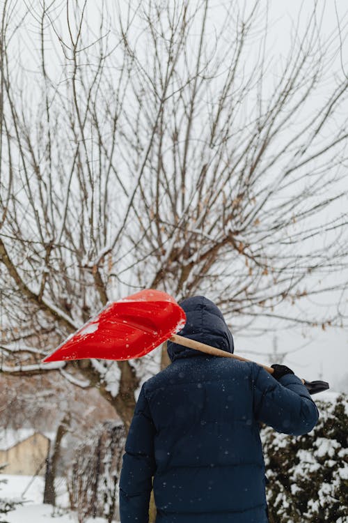 Free A Person Carrying a Snow Shovel Over His Shoulder Stock Photo