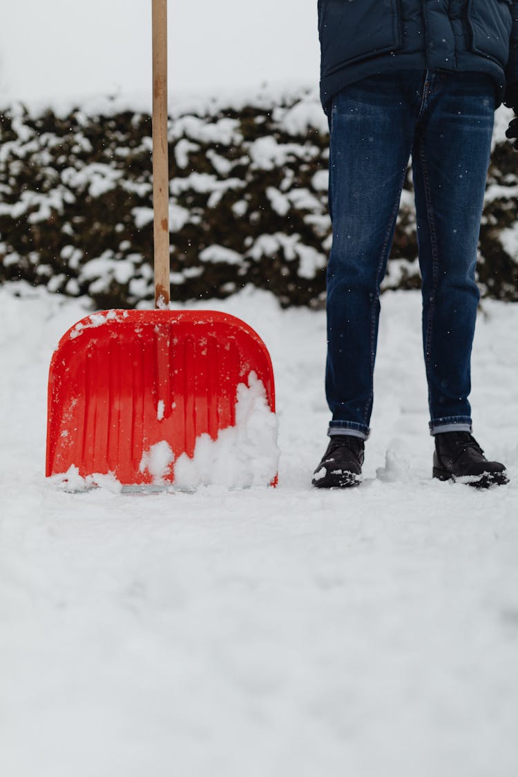 A Person Standing Over Snow Covered Ground With A Shovel