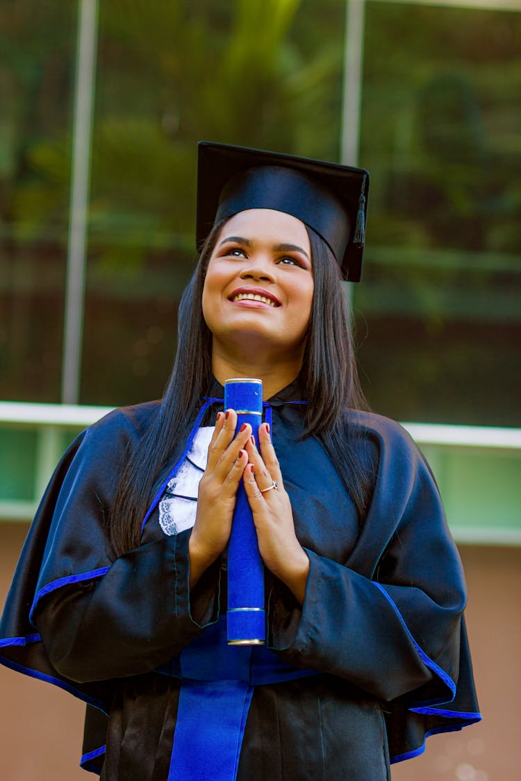 Happy Girl In Graduation Mantle And Cap Holding Diploma