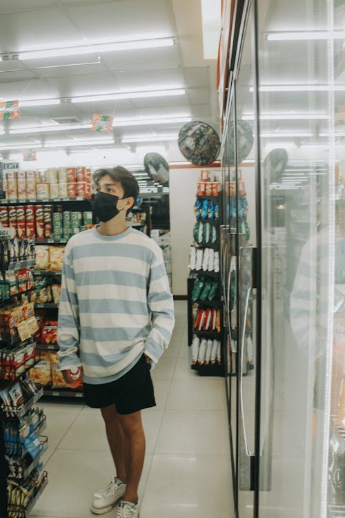 Man in Striped Long Sleeve Shirt Standing Near Display Shelf