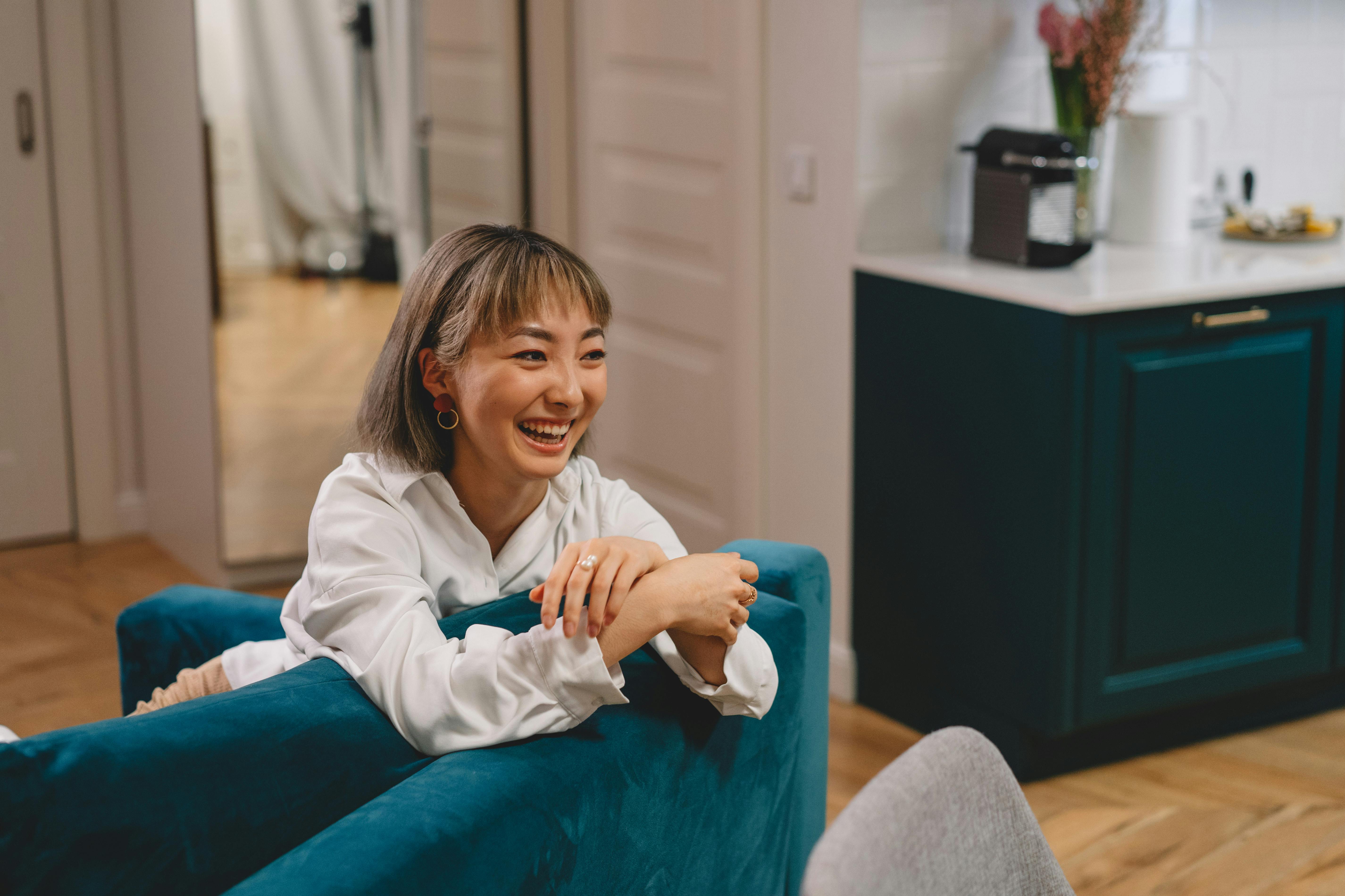 A person with a warm, genuine smile and friendly eye contact, leaning in slightly as if listening intently and engaging in a positive conversation.