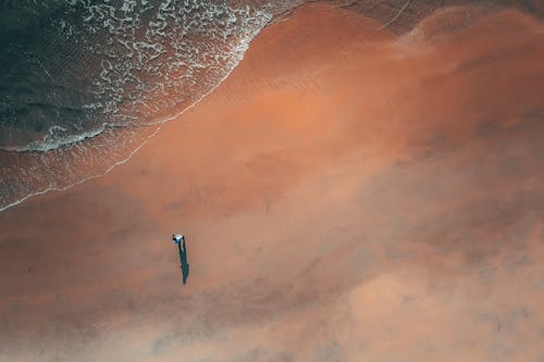 Faceless tourist admiring foamy sea from sandy beach