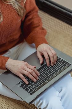 From above crop anonymous female in casual clothes browsing modern netbook and sitting on chair