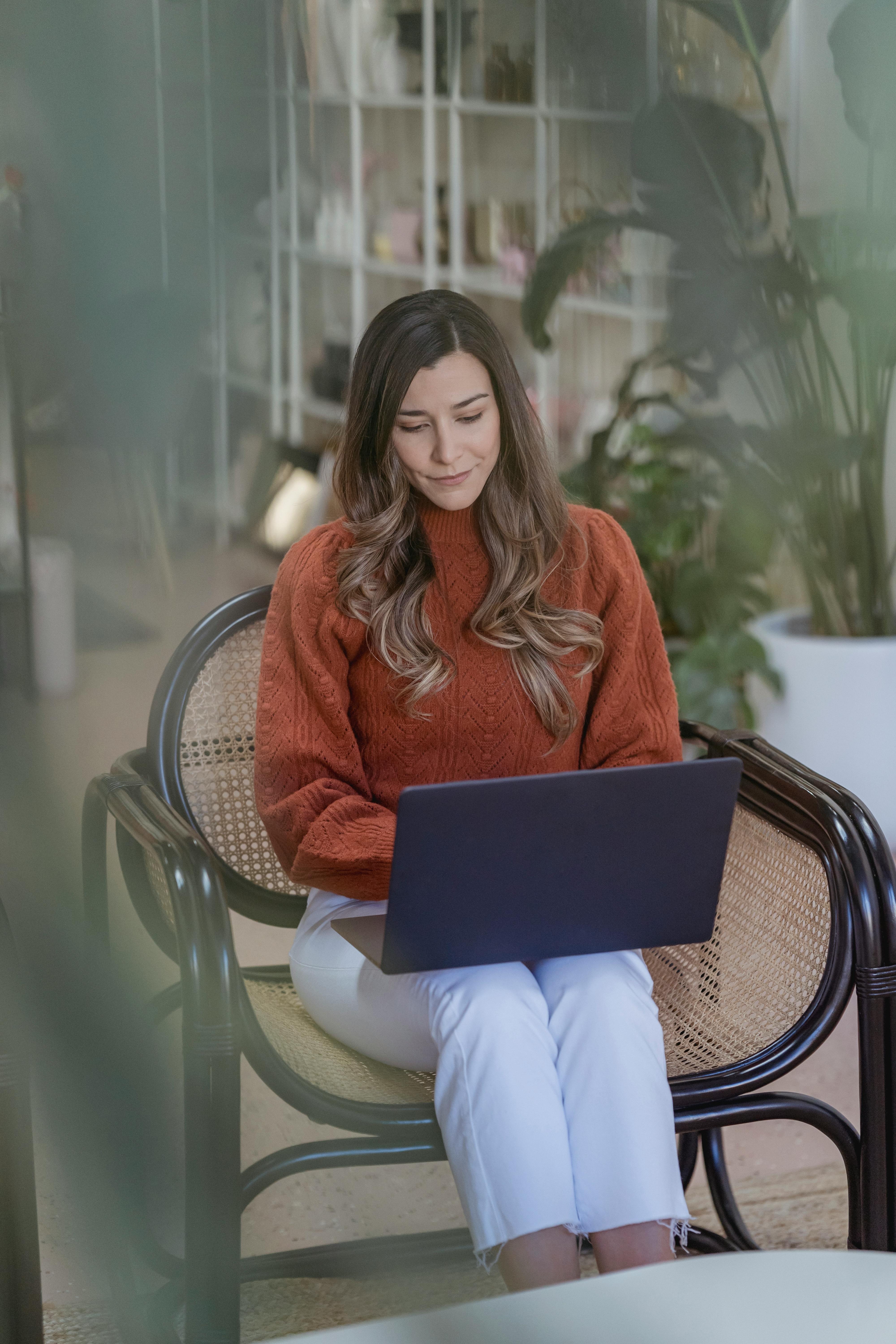 young woman using laptop on armchair