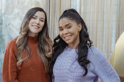 Diverse women with long hair in woolen stylish casual sweaters smiling and looking at camera