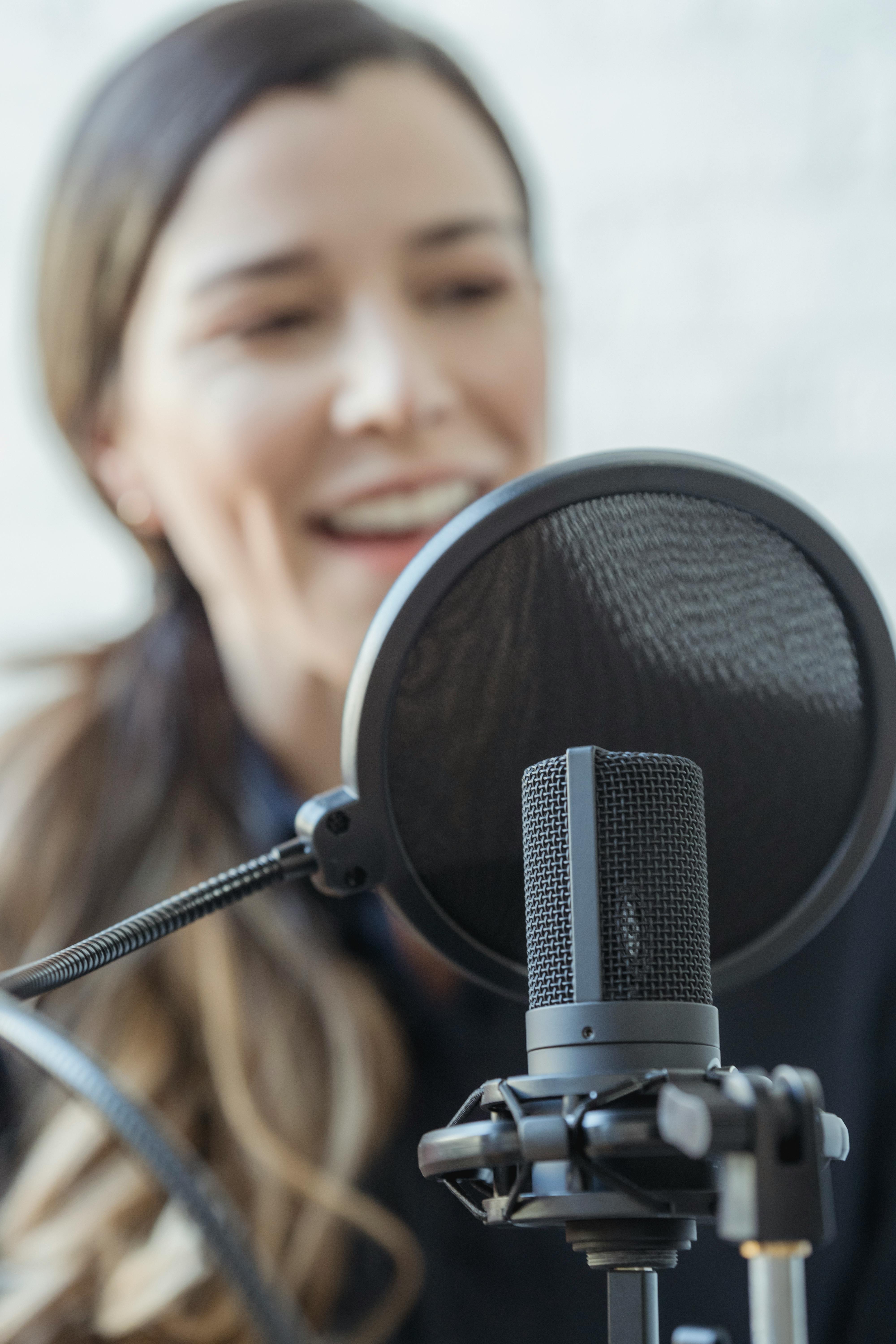 happy woman smiling while recording voice with microphone