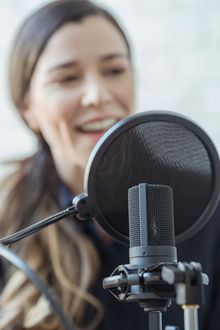 Presenter laughing behind a pop filter — photo by George Milton on Pexels