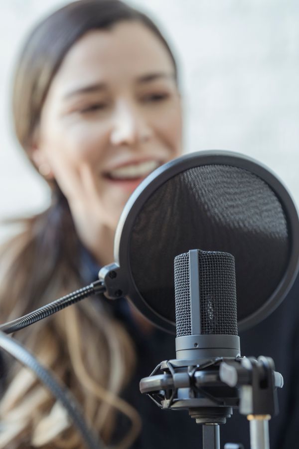 Writer recording an episode at a desk microphone, photo by George Milton on Pexels