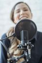 Positive woman smiling and recording audio message with microphone