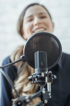 A woman smiles while recording with a professional microphone. Perfect for media and broadcasting themes.