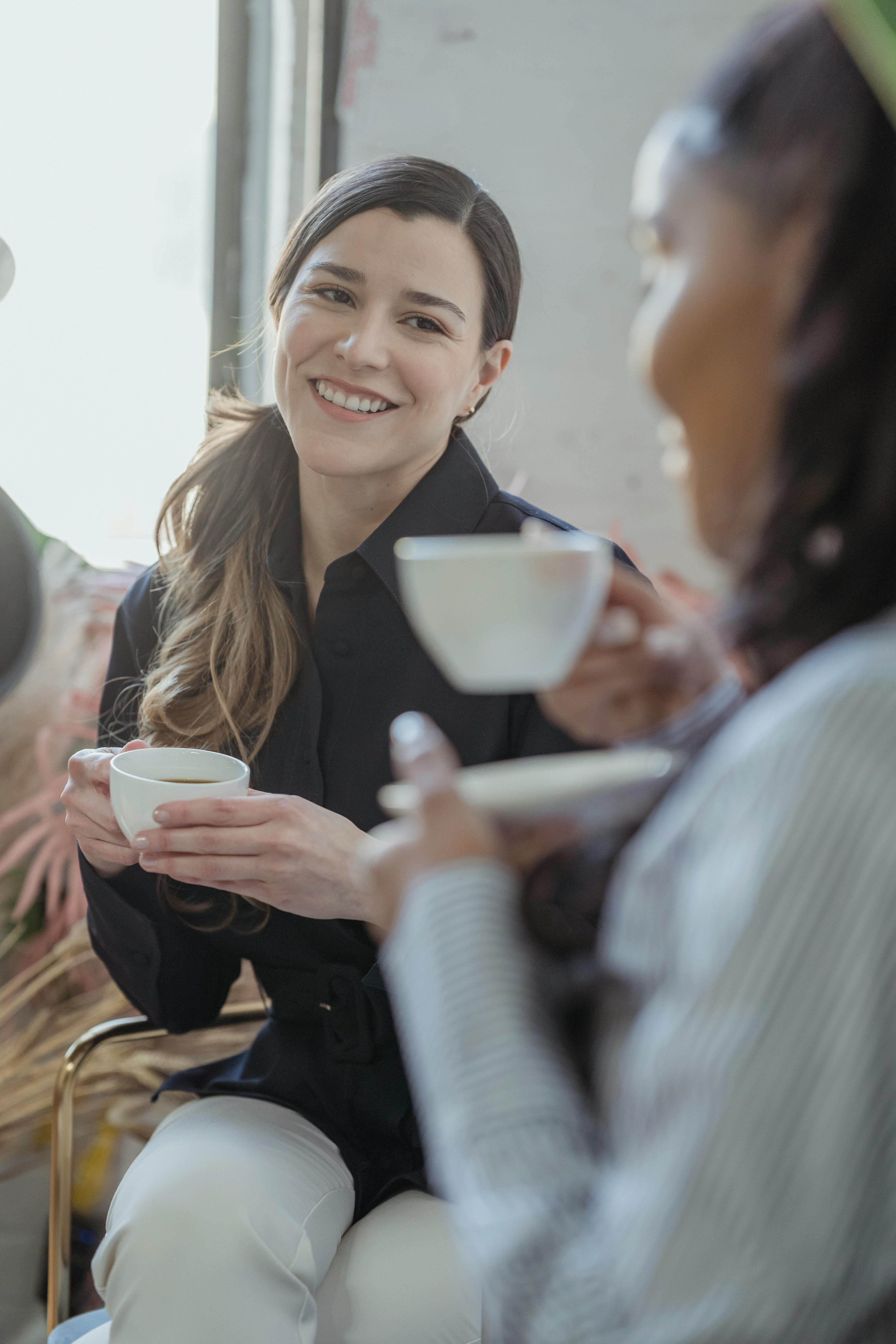 positive diverse friends talking and having cup of coffee