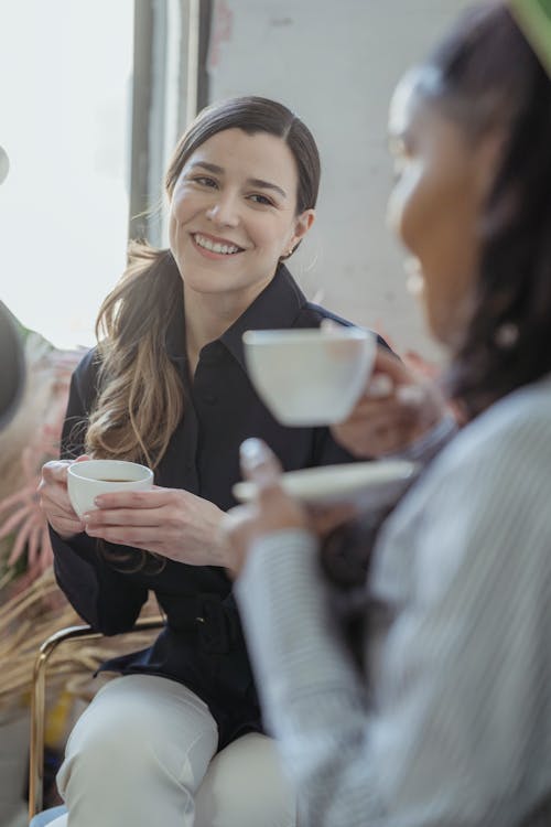 Free Positive diverse friends talking and having cup of coffee Stock Photo
