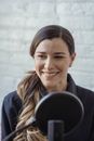 Delighted woman with long wavy hair smiling and recording interview
