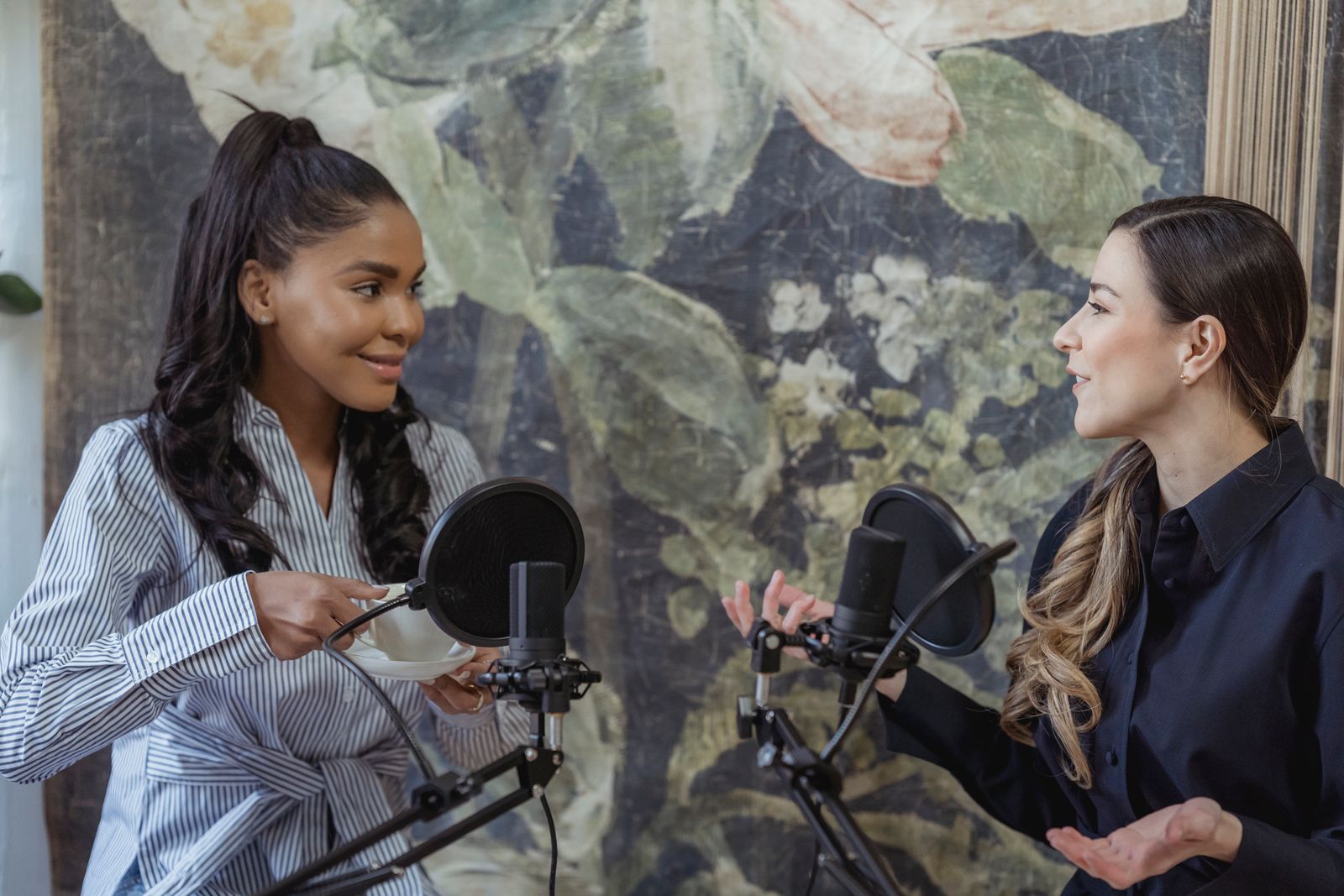 Two hosts recording a podcast conversation at microphones