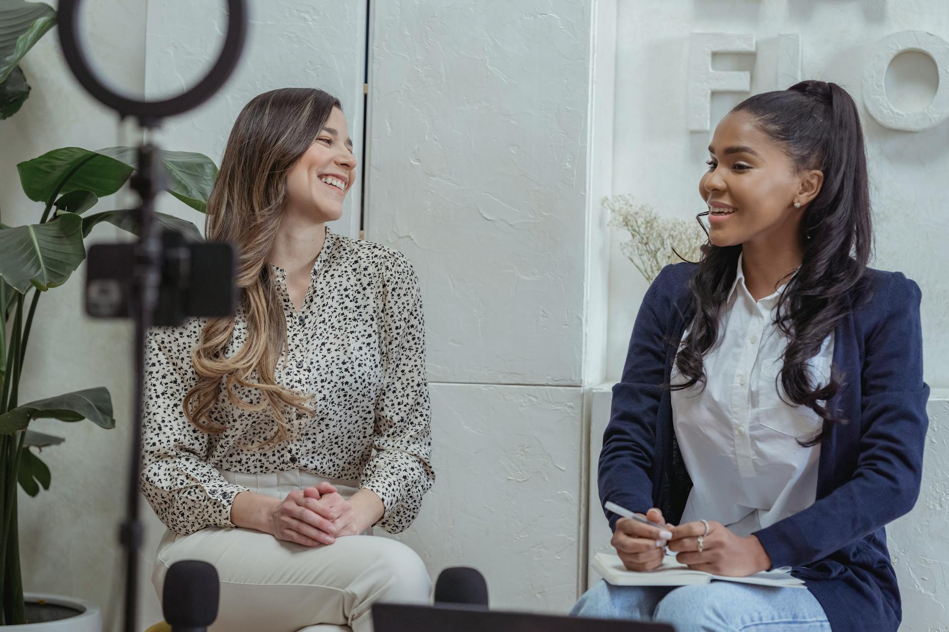 Two women engaged in a lively conversation in a professional interview setting.