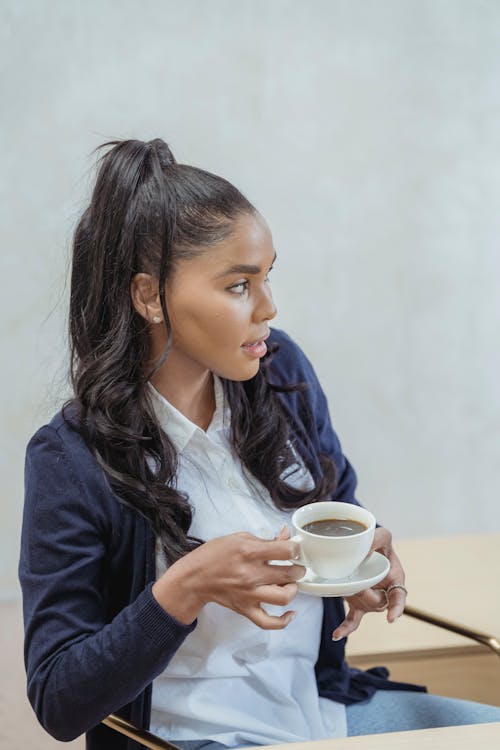Free A Woman in Blue Blazer Holding a Ceramic Mug and Saucer Stock Photo