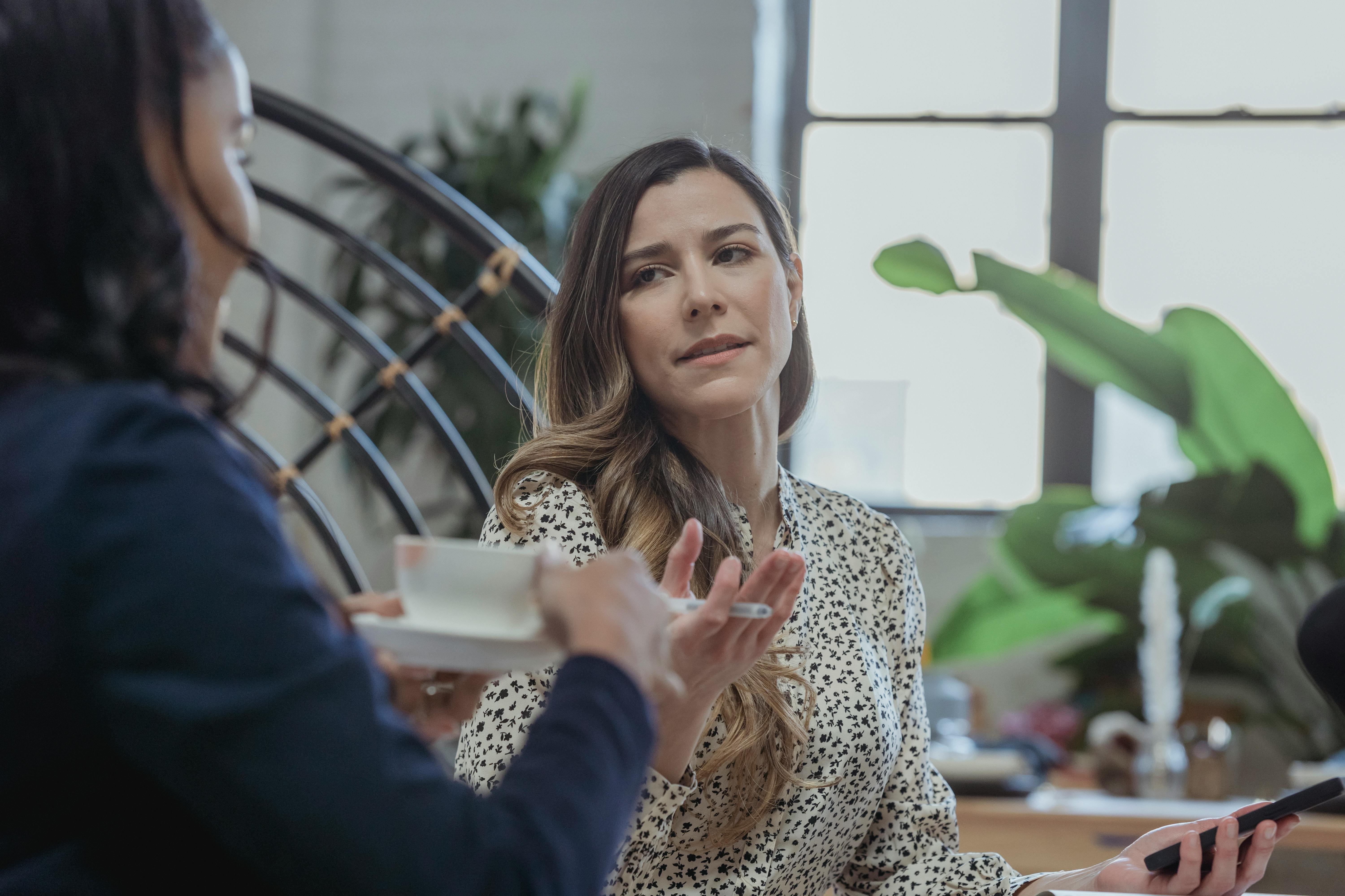 woman discussing work with black colleague drinking coffee