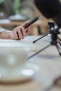 Crop unrecognizable woman using smartphone at desk with microphones