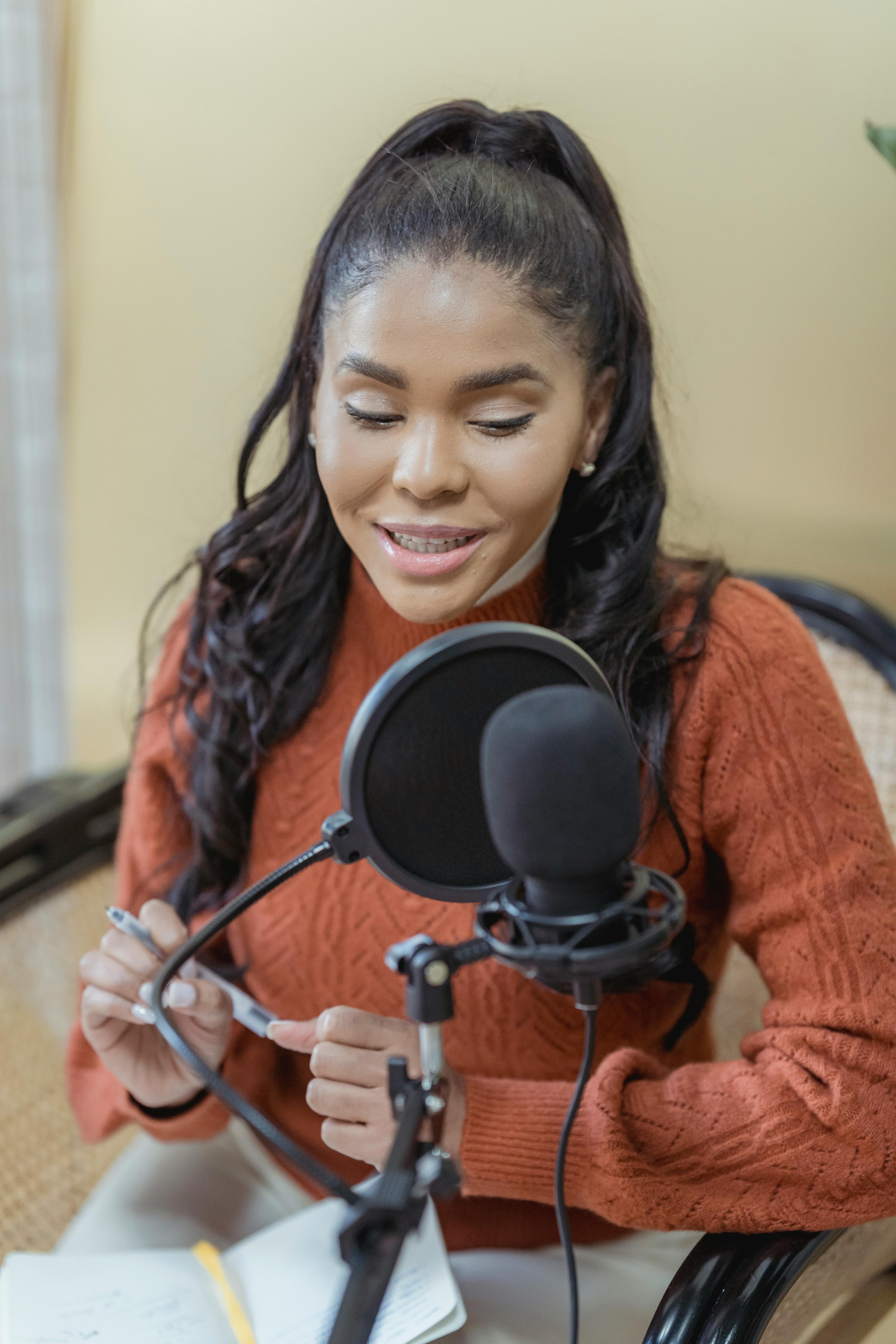 trendy young black woman recording audio with microphone in studio