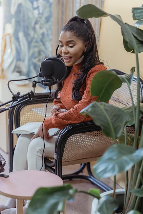 Free Stylish young ethnic lady recording podcast in light studio Stock Photo