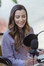 Smiling woman writing in planner while recording podcast