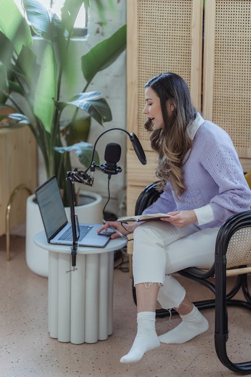 Female radio host broadcasting from home and using laptop