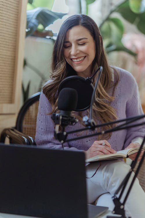 Smiling woman recording voice podcast in microphone