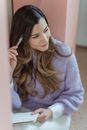 Pensive dreamy female writing notes in planner