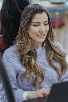 Smiling woman working on a laptop, representing modern office work culture.