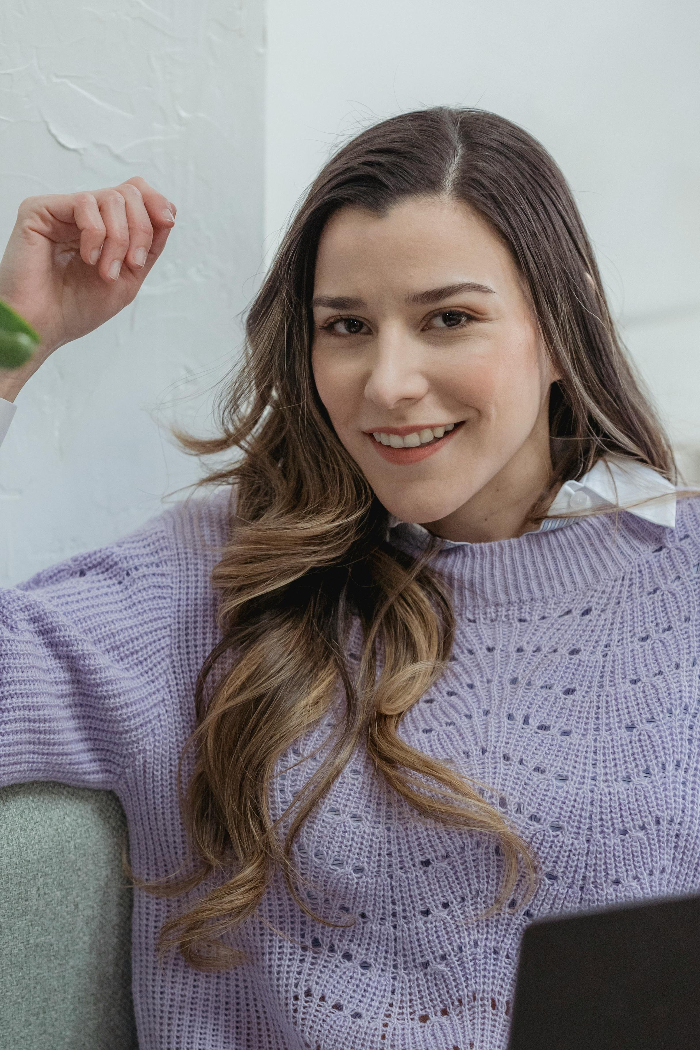 Charming portrait of a young woman with wavy hair and a warm smile, indoors.